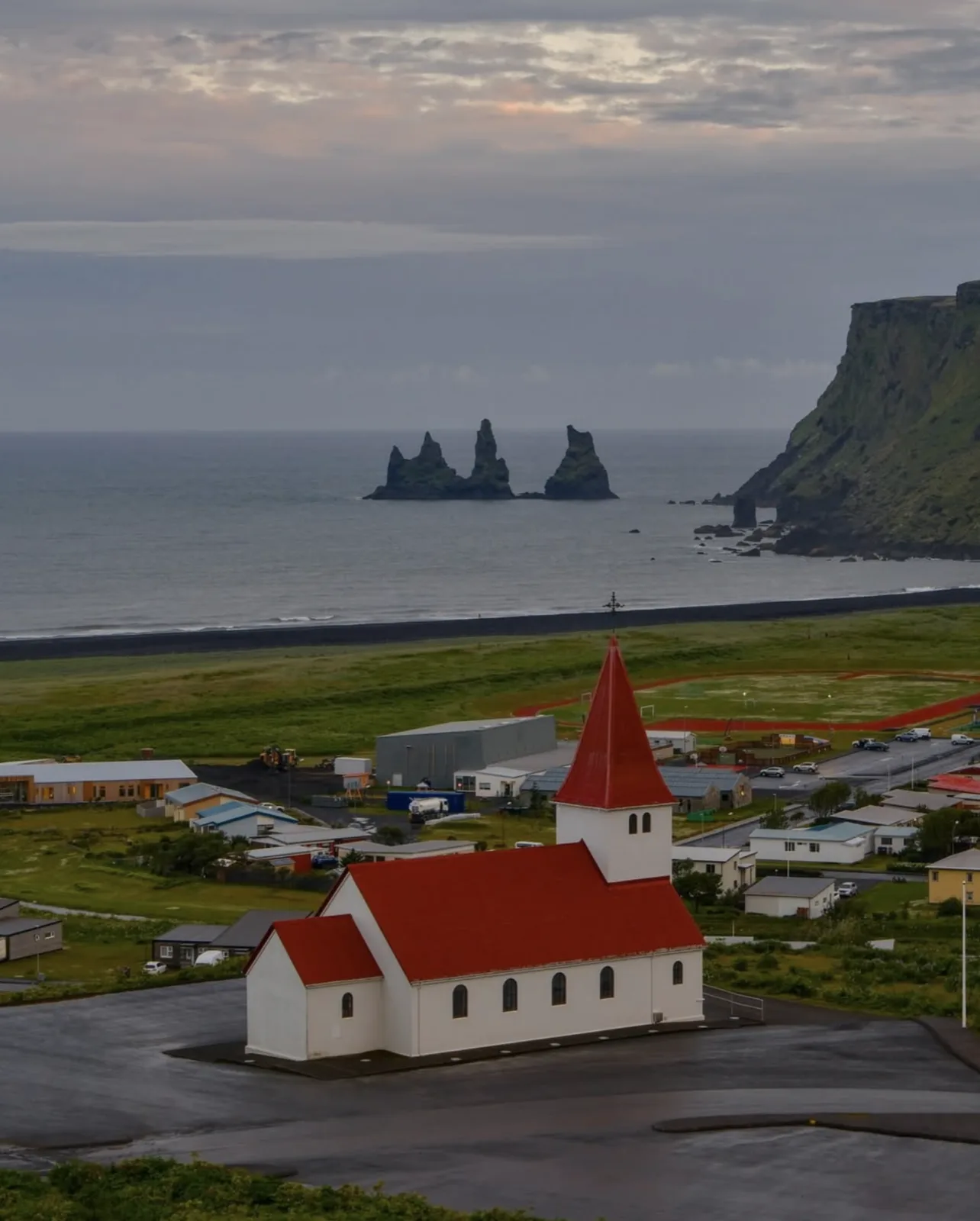 A red-roofed church above a coastal village